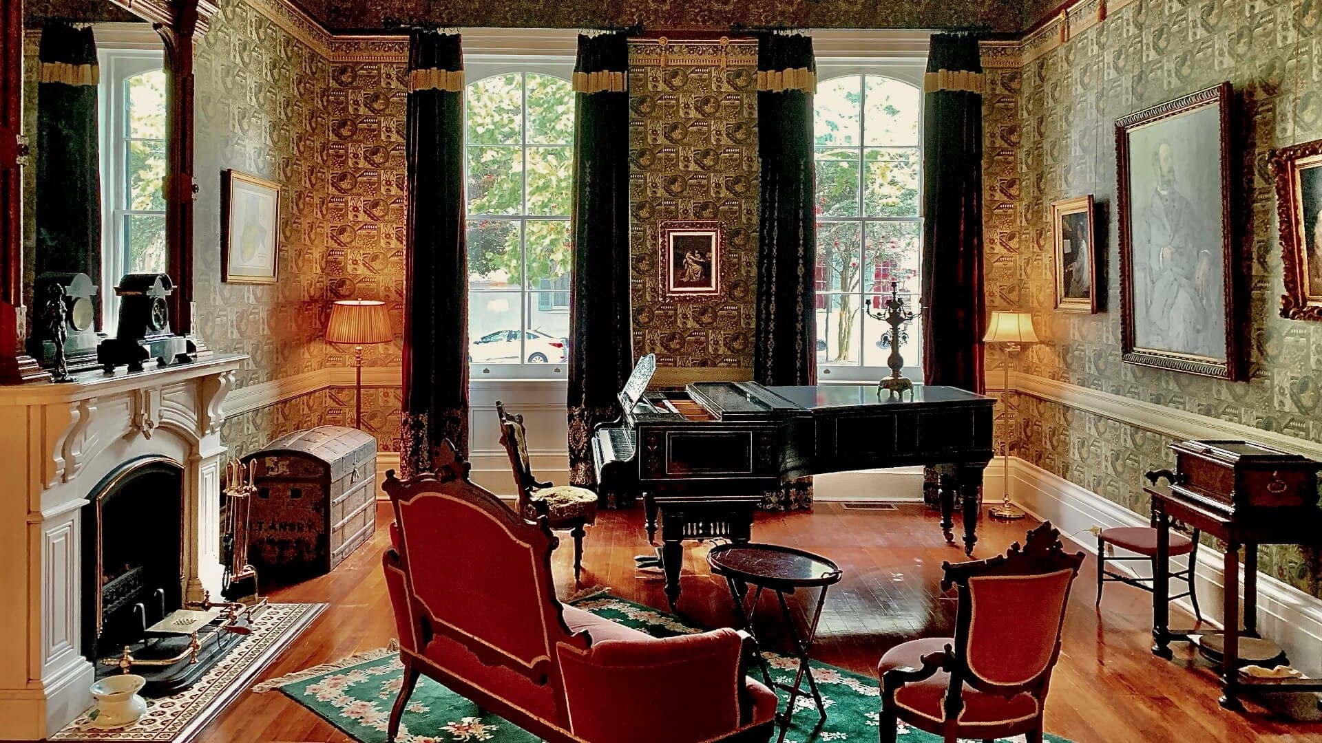 A vintage room featuring a grand piano, elegant furniture, and decorative wallpaper.
